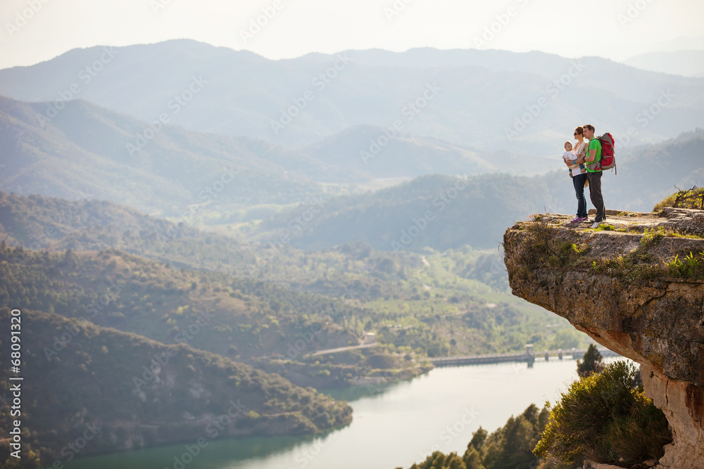 Young couple with toddler boy in sling standing on cliff
