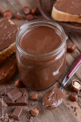 Sweet chocolate cream in jar on table close-up