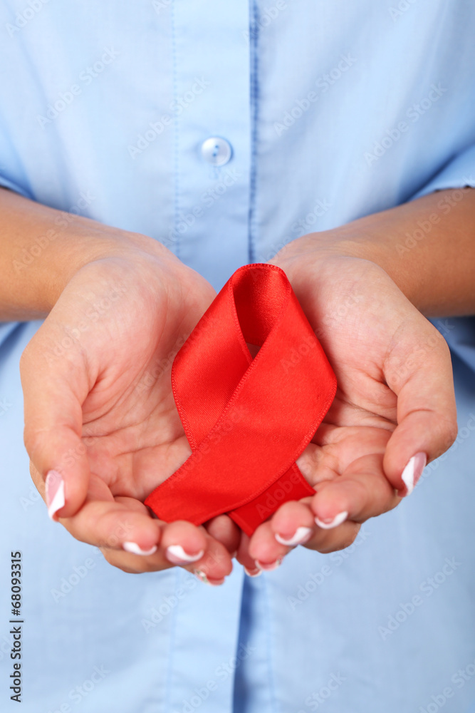 Woman with aids awareness red ribbon in hands, close-up