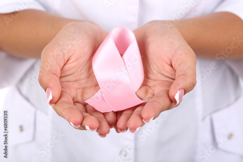 Woman with aids awareness pink ribbon in hands, close-up