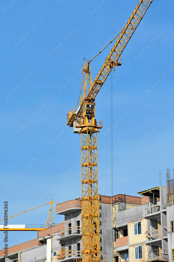 Crane and building construction site against blue sky