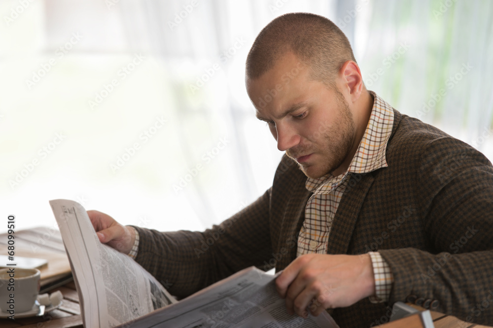 Naklejka premium Businessman reading newspaper cafe