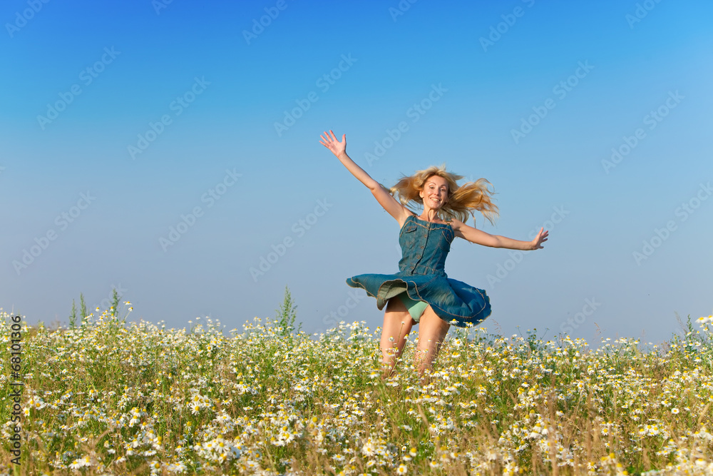 The happy young woman in the field of camomiles