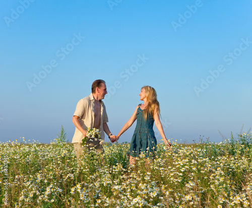 The happy young pair in the field of chamomiles