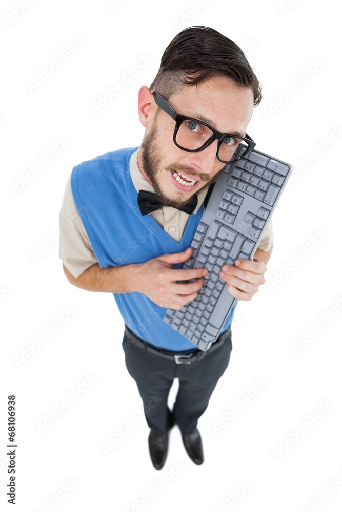 Geeky hipster looking at camera holding keyboard Geeky hipster looking at camera holding keyboard