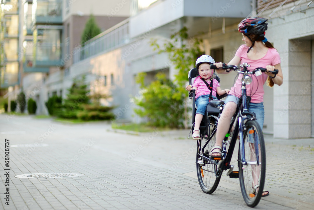 Fototapeta premium Young mother and her toddler girl riding a bicycle