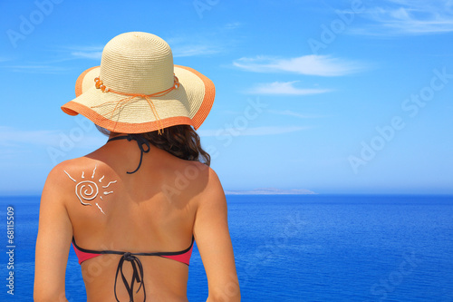 Sun made of sunblock on woman back with seascape background