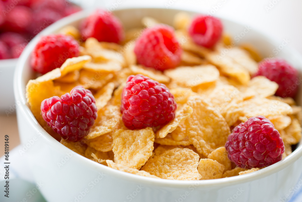 Cornflakes and red rasberries in a white bowl Cornflakes and red rasberries in a white bowl