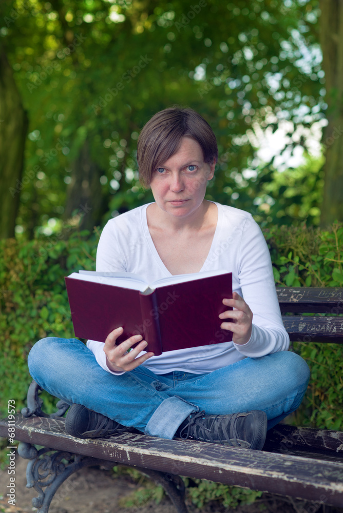 Obraz premium Woman reading book in the park