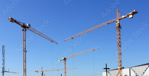 The construction cranes on blue sky background