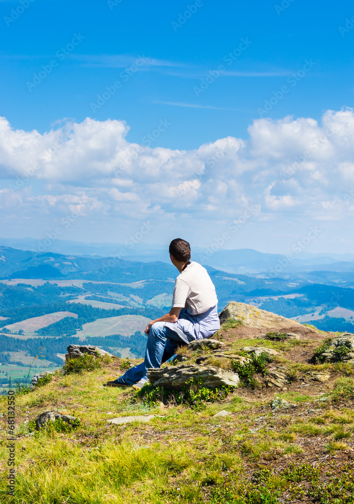 Man sitting and looking at mountains Man sitting and looking at mountains