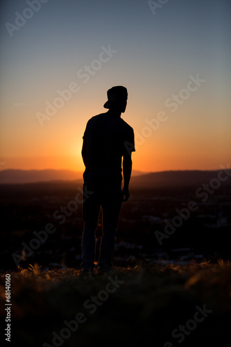 silhouetted male youth in sunset with hat