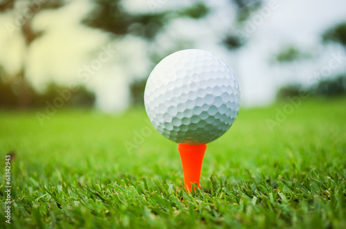 golf ball with orange tee on green grass