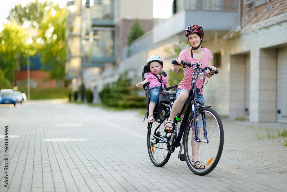 Young mother and her toddler girl riding a bicycle