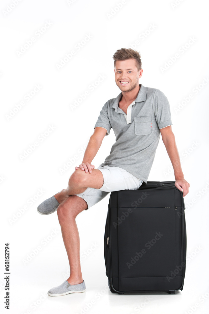 handsome guy sitting on luggage and smiling. handsome guy sitting on luggage and smiling.