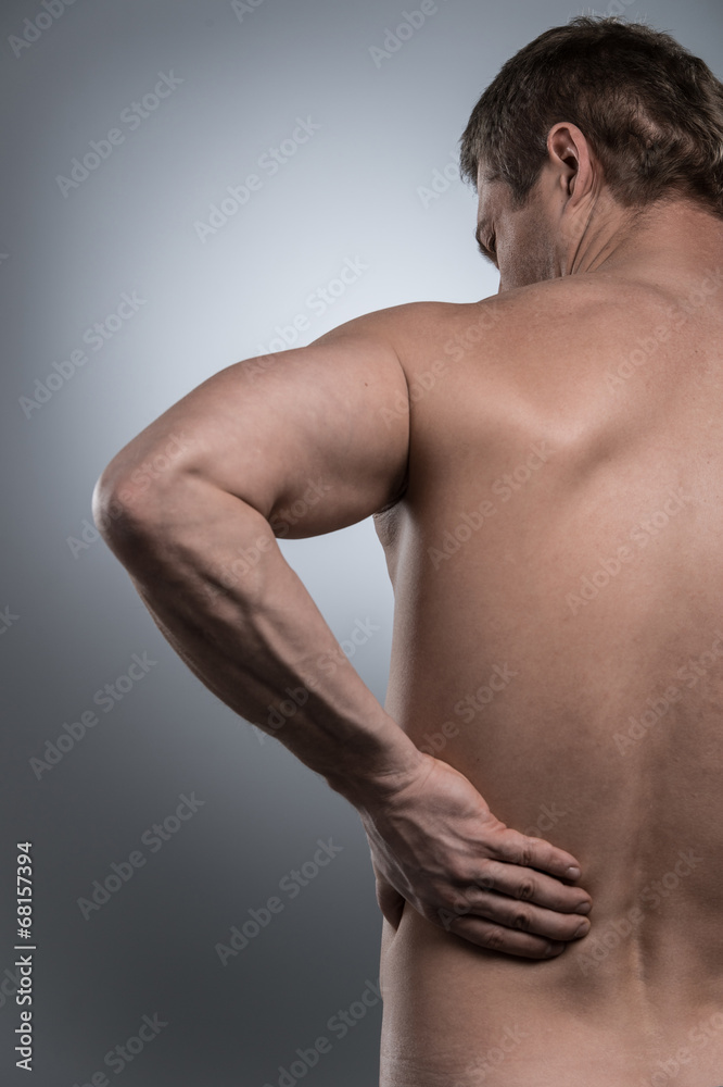 back view of young shirtless man with back pain. back view of young shirtless man with back pain.
