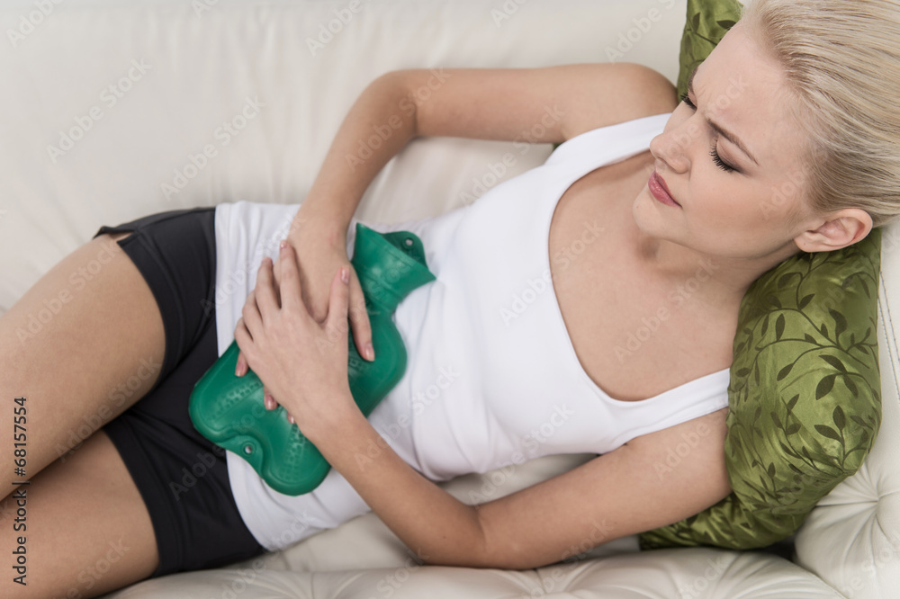 Beautiful young woman in bed, with hot water bag on her tummy. Beautiful young woman in bed, with hot water bag on her tummy.