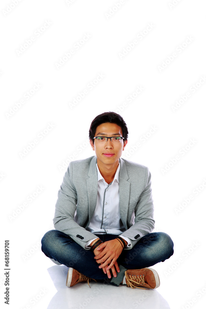 Handsome asian man sitting on the floor over white background Handsome asian man sitting on the floor over white background