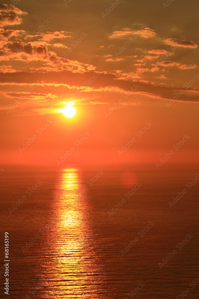 Orange sun with reflection on surface of the sea