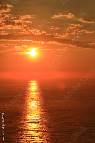 Orange sun with reflection on surface of the sea