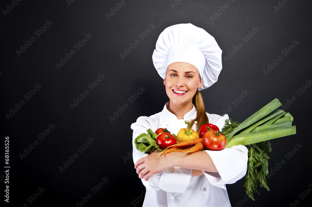 Woman chef holding vegetables and smiling over dark background Woman chef holding vegetables and smiling over dark background