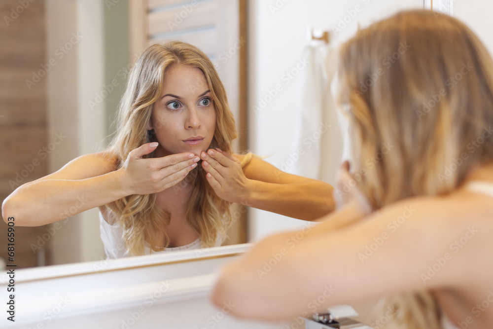 Woman removing pimple from her face Woman removing pimple from her face