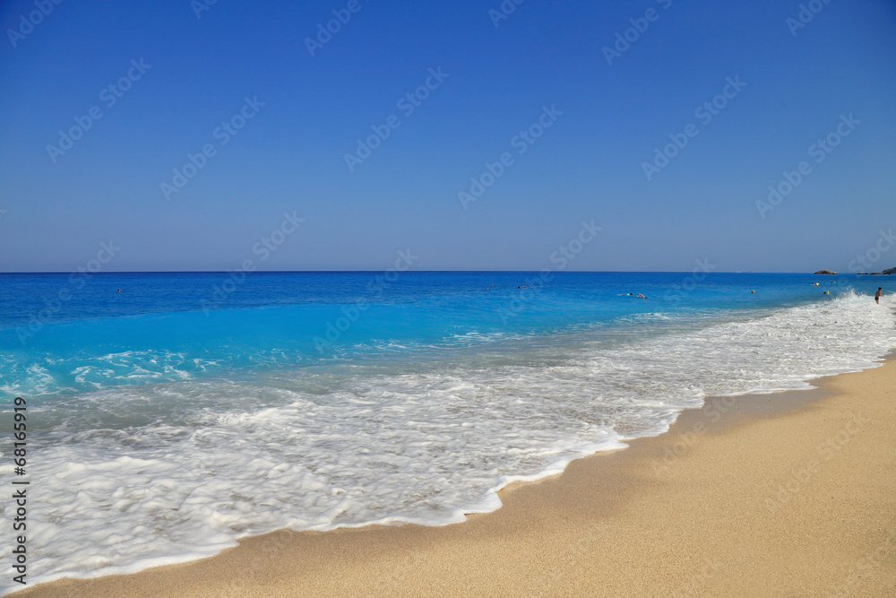 Sandy seashore with blue sky and water