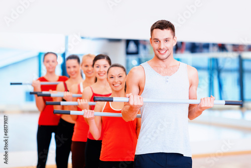 group of smiling people working out with barbells