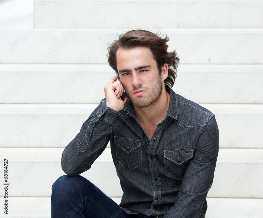 Cool guy sitting outside with mobile phone Cool guy sitting outside with mobile phone
