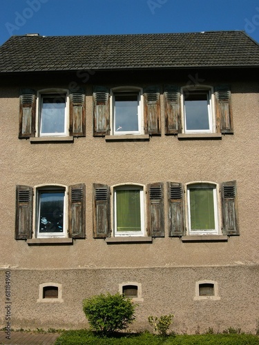 Altes Wohnhaus in Umbra und Naturfarben mit traditionellen Fensterläden aus Holz im Sommer bei blauem Himmel und Sonnenschein in Wettenberg Krofdorf-Gleiberg bei Gießen in Hessen photo