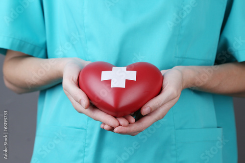 Red heart with cross sign in doctor hand, close-up,