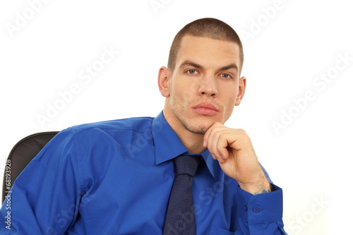 Contemplating young businessman at blue shirt sitting on a chair