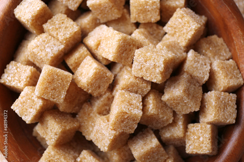 Brown sugar cubes in bowl on sackcloth background