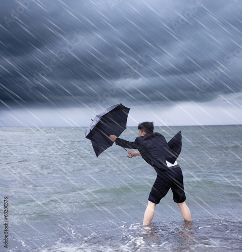 Obraz na płótnie business man holding a umbrella to resist rainstorm