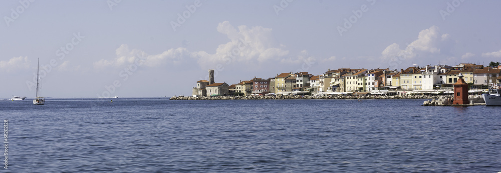 Piran town panorama with sailboat and a red lighthouse