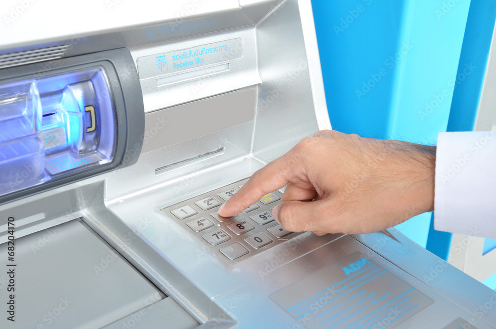 ATM (Automated Teller Machine) with hand pressing on the keypad ATM (Automated Teller Machine) with hand pressing on the keypad