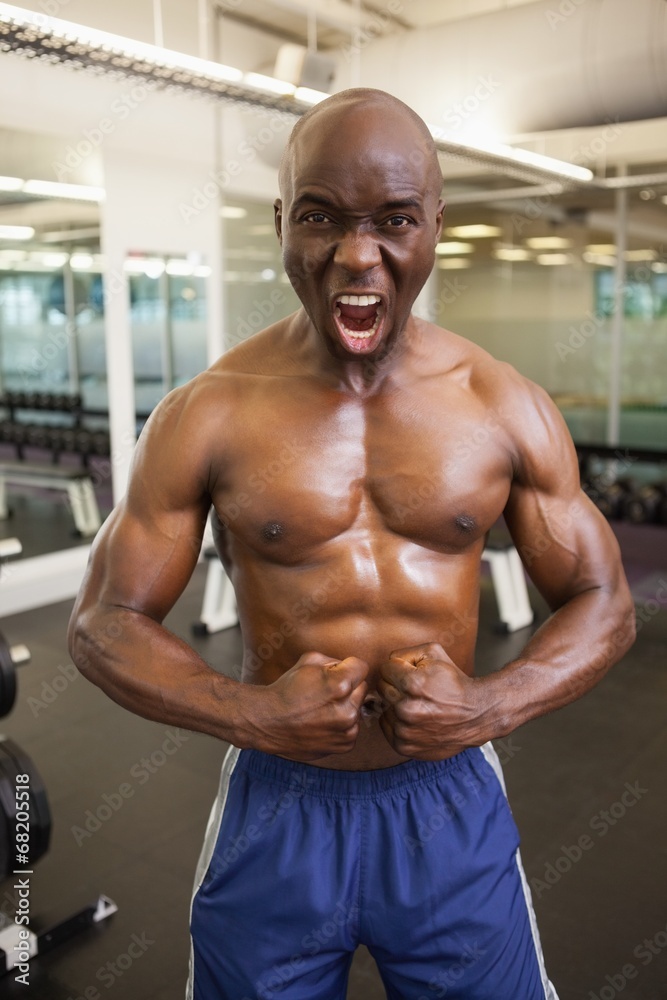 Muscular man shouting while flexing muscles in gym Muscular man shouting while flexing muscles in gym