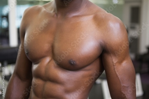 Mid section of a muscular shirtless man in gym