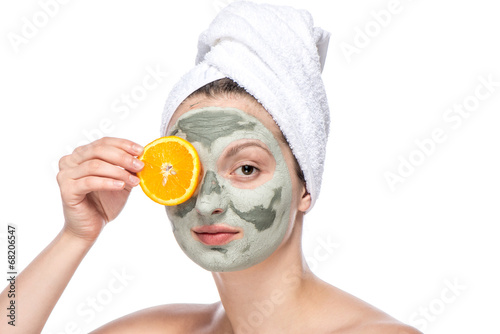 Beautiful woman with facial mask and orange