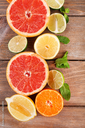 Different sliced juicy citrus fruits on wooden table