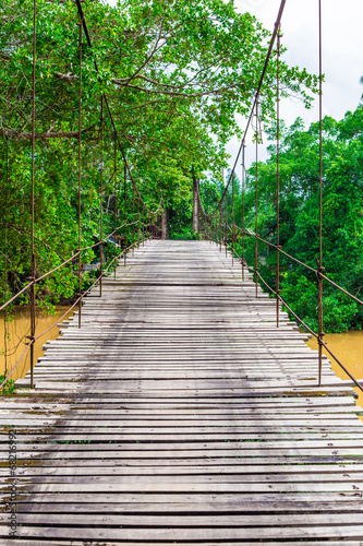 Old wooden long rope bridge cross the stream