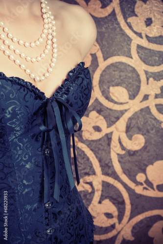 woman wearing black corset and pearls against retro background