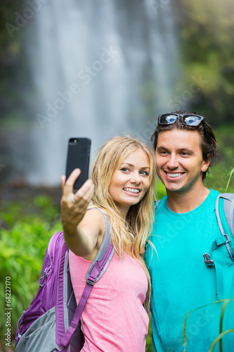 Couple having fun taking pictures together outdoors on hike