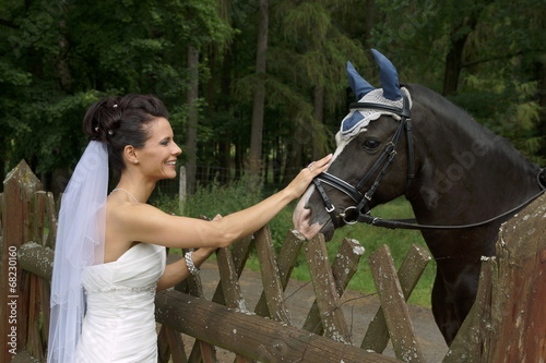 Young bride stroking horse in forest park