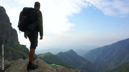 Young man standing on top of a rock high in the mountains