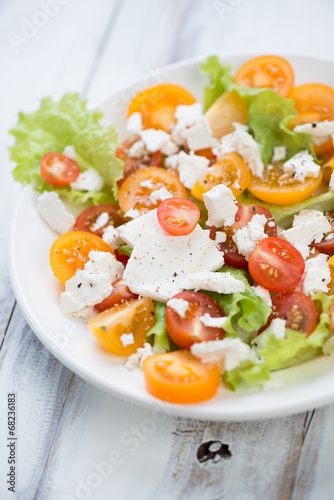 Vegetable salad with feta cheese on a glass plate, close-up