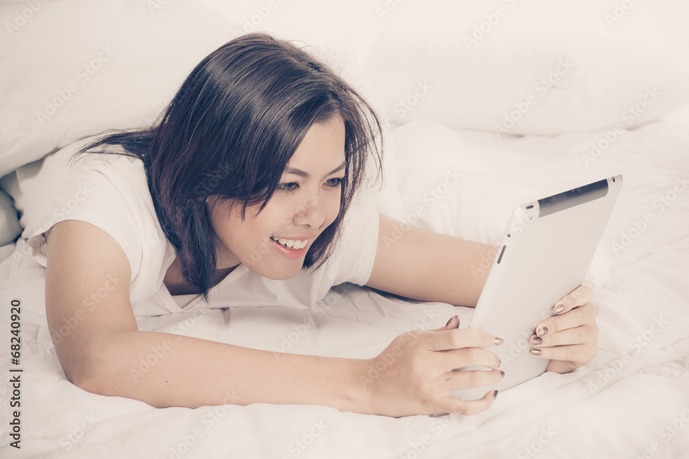 Young beautiful woman in bed, working or relaxing with her compu Young beautiful woman in bed, working or relaxing with her compu