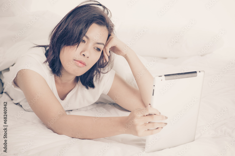 Young beautiful woman in bed, working or relaxing with her compu Young beautiful woman in bed, working or relaxing with her compu
