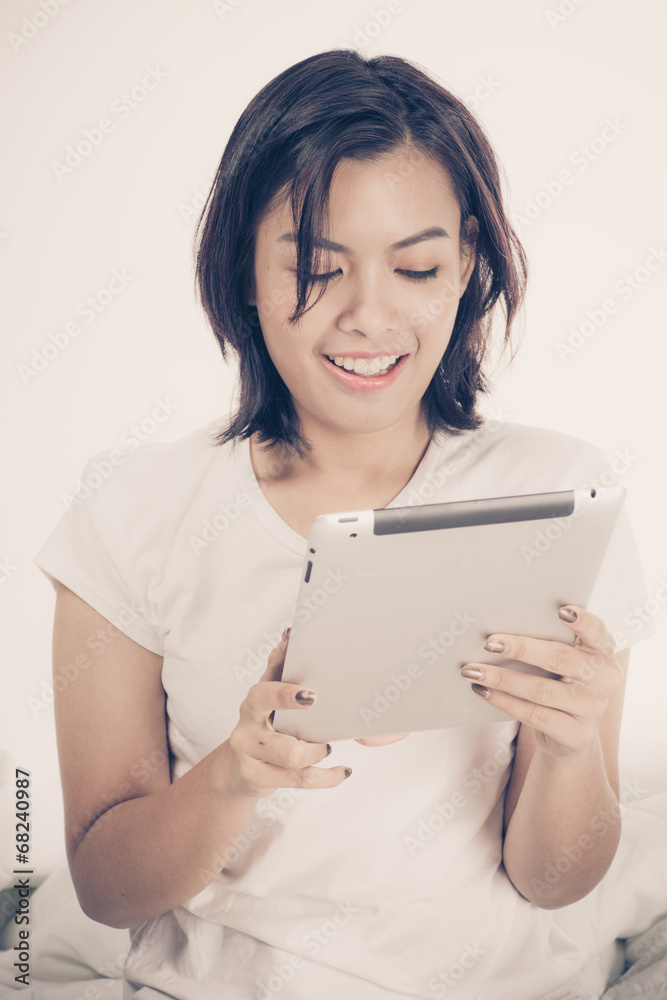 Young beautiful woman in bed, working or relaxing with her compu Young beautiful woman in bed, working or relaxing with her compu