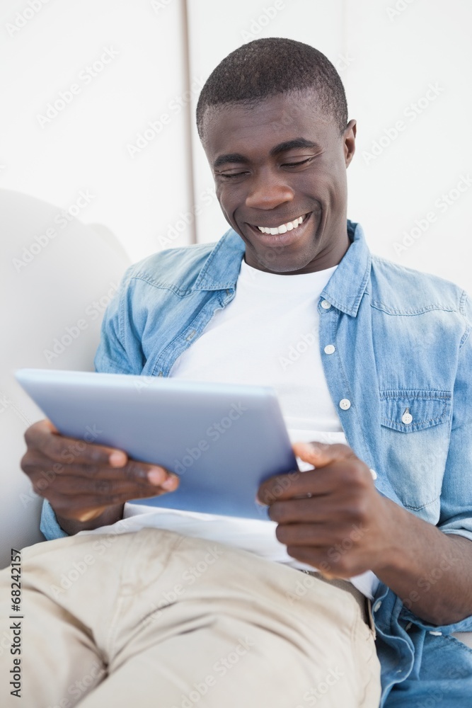 Casual man lying on sofa using his tablet pc Casual man lying on sofa using his tablet pc